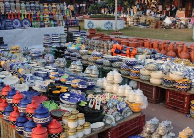 Vibrant ceramic pots and vases on display in an outdoor market setting, showcasing diverse handcrafted designs.