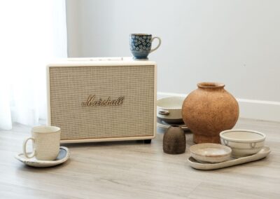 A vintage Marshall speaker with diverse ceramic dishware on a hardwood floor in Hanoi.