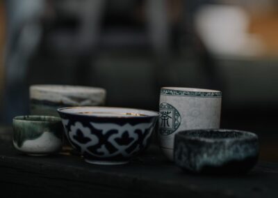A collection of intricately designed ceramic bowls and cups displayed on a dark surface.