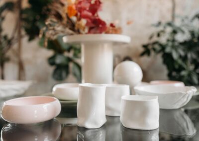 Close-up of elegant handmade ceramic pottery and tableware on a stylish glass table.